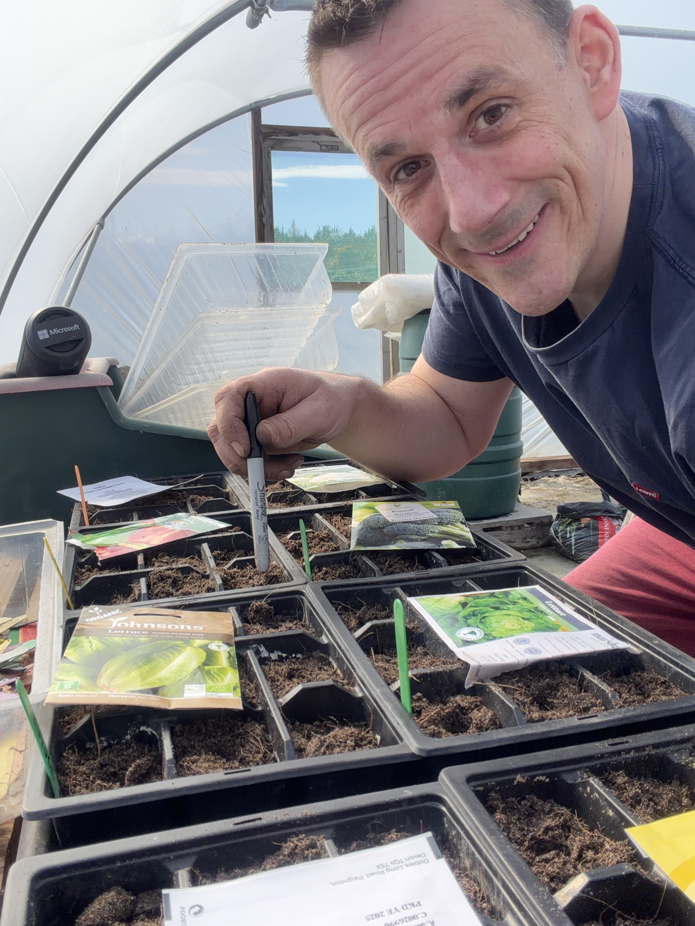 Damo grinning in the polytunnel with freshly planted seed trays